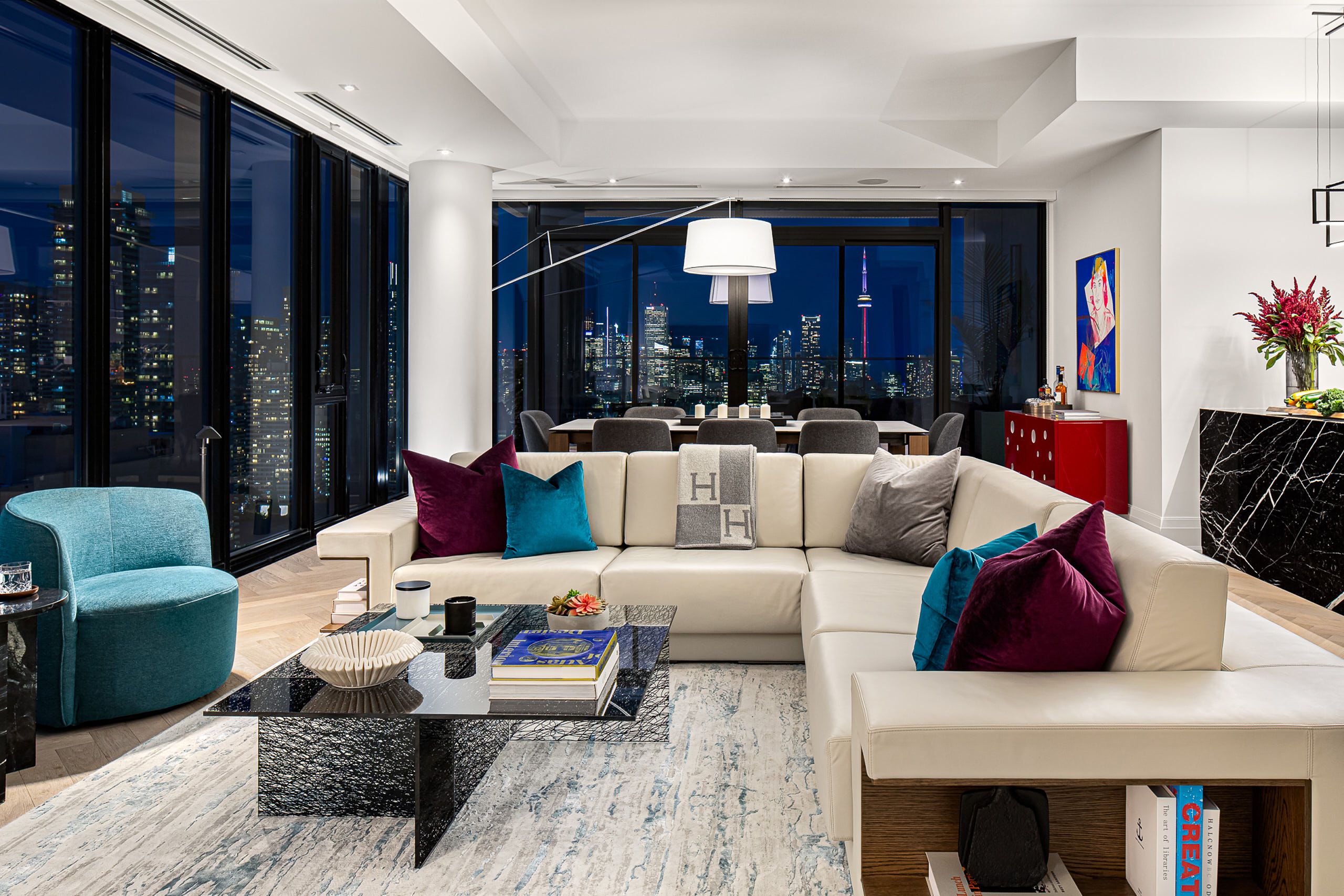 Night shot of the Yorkville living area with glowing city lights visible through expansive floor-to-ceiling windows.