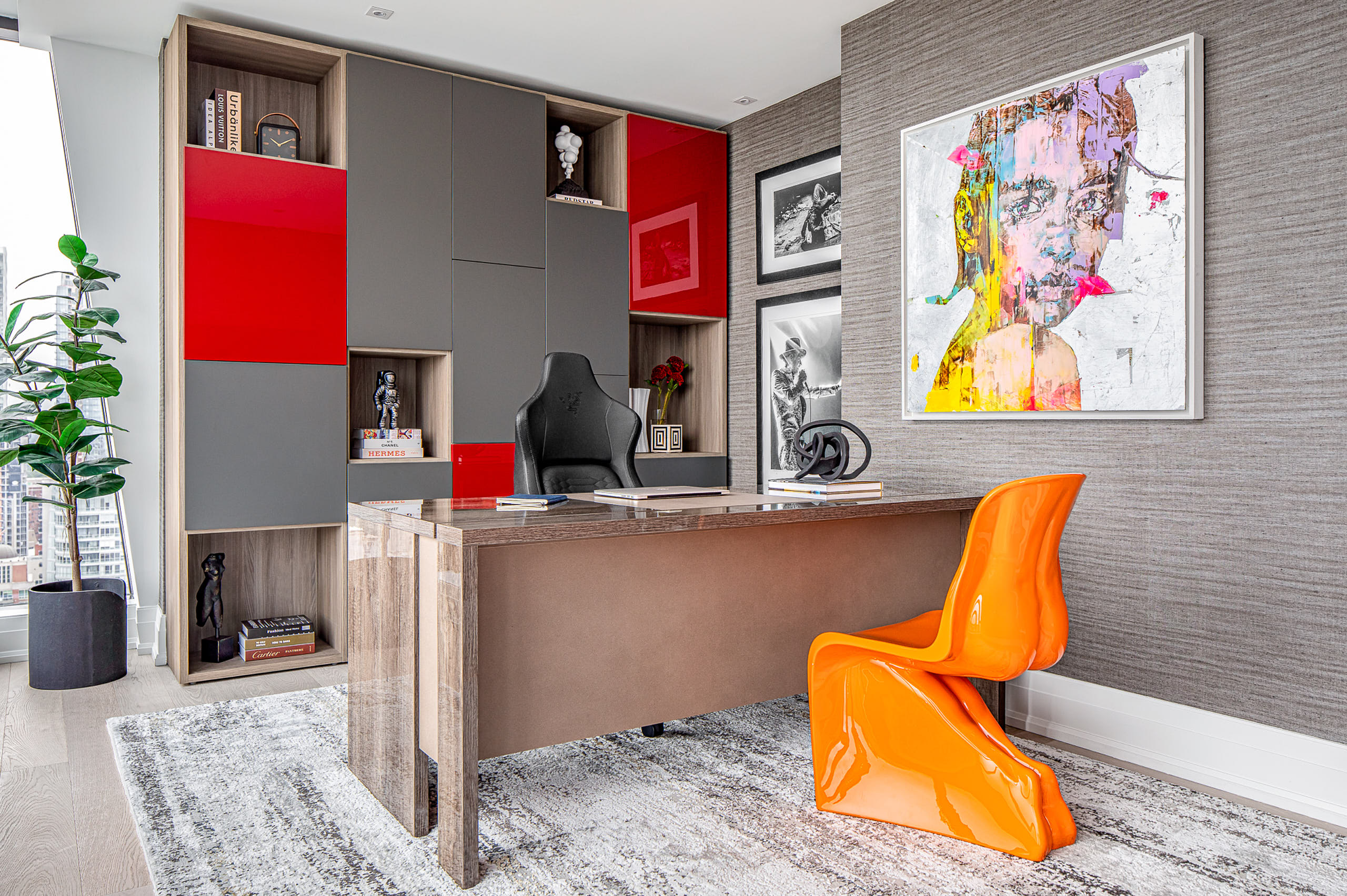 Sophisticated Yorkville home office featuring a glossy orange "Him" chair, custom grey and red millwork, and vibrant original portrait art.