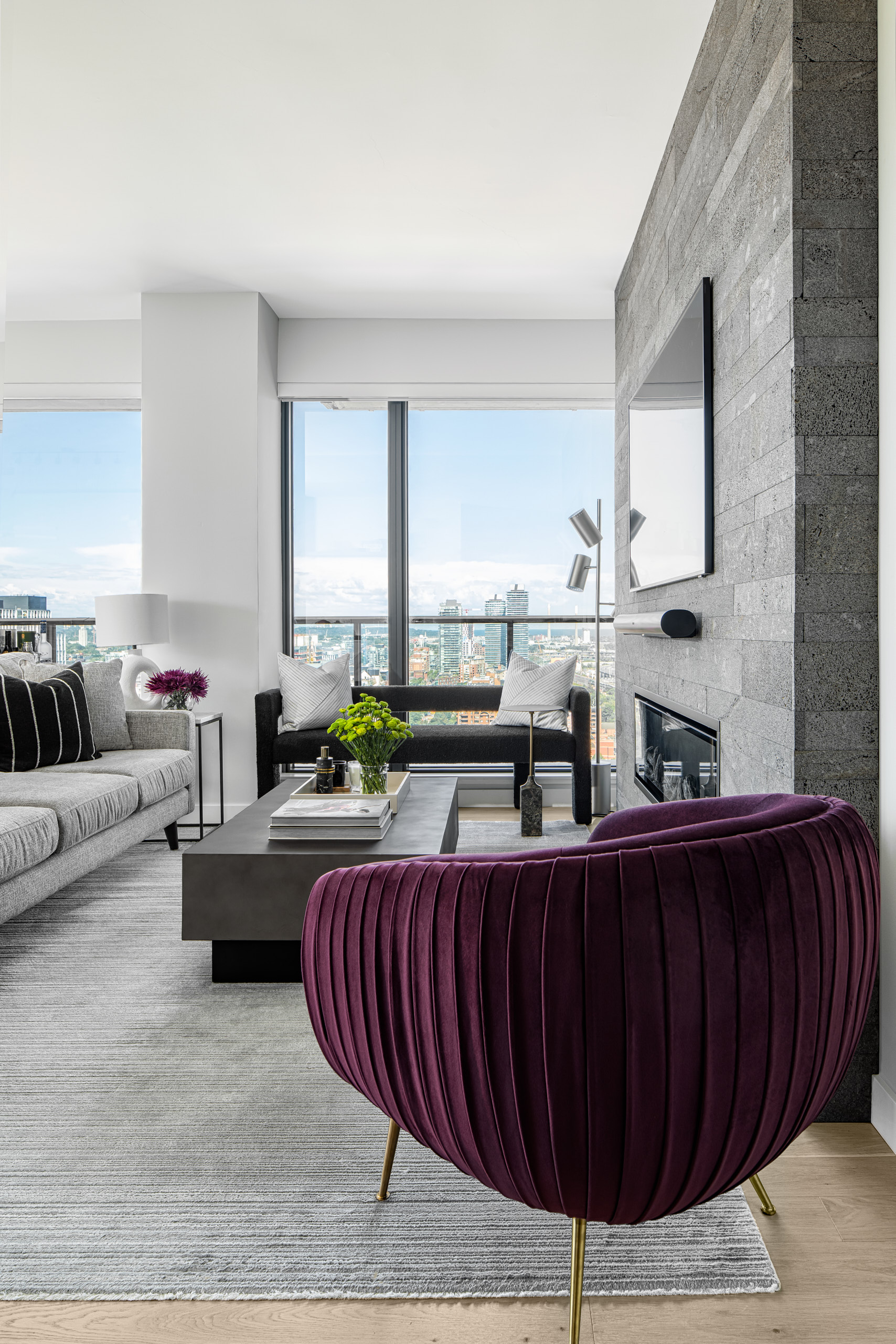 Grey living room with a Lavastone fireplace and a vibrant purple pleated velvet armchair