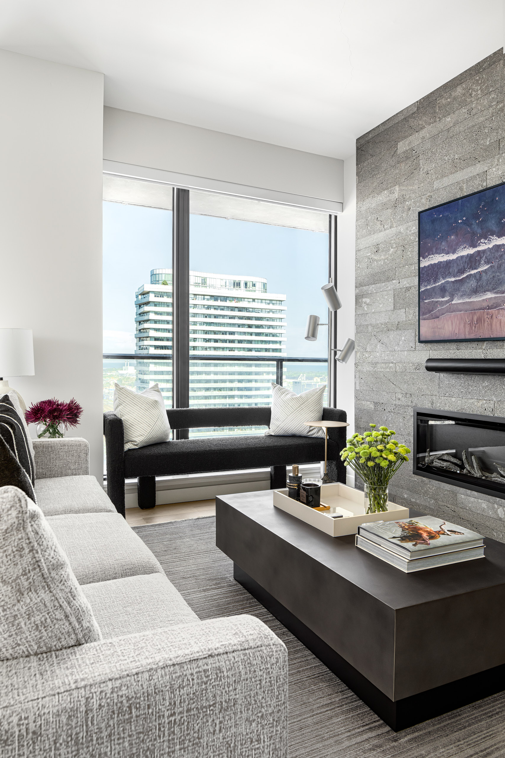 Modern living room with a grey sofa, dark coffee table, and a grey Lavastone fireplace wall