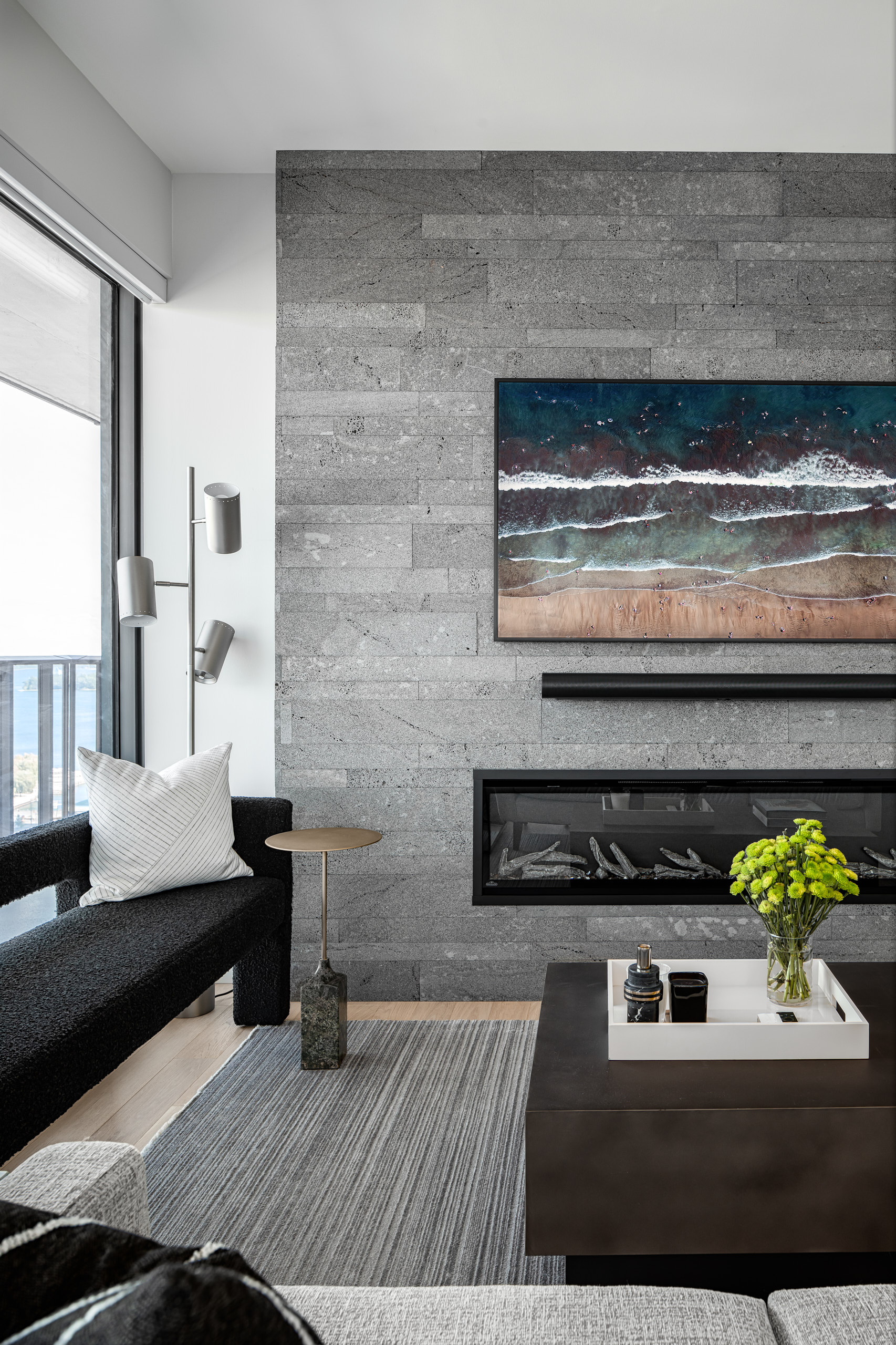 Black textured bench and a small brass side table next to a grey Lavastone fireplace