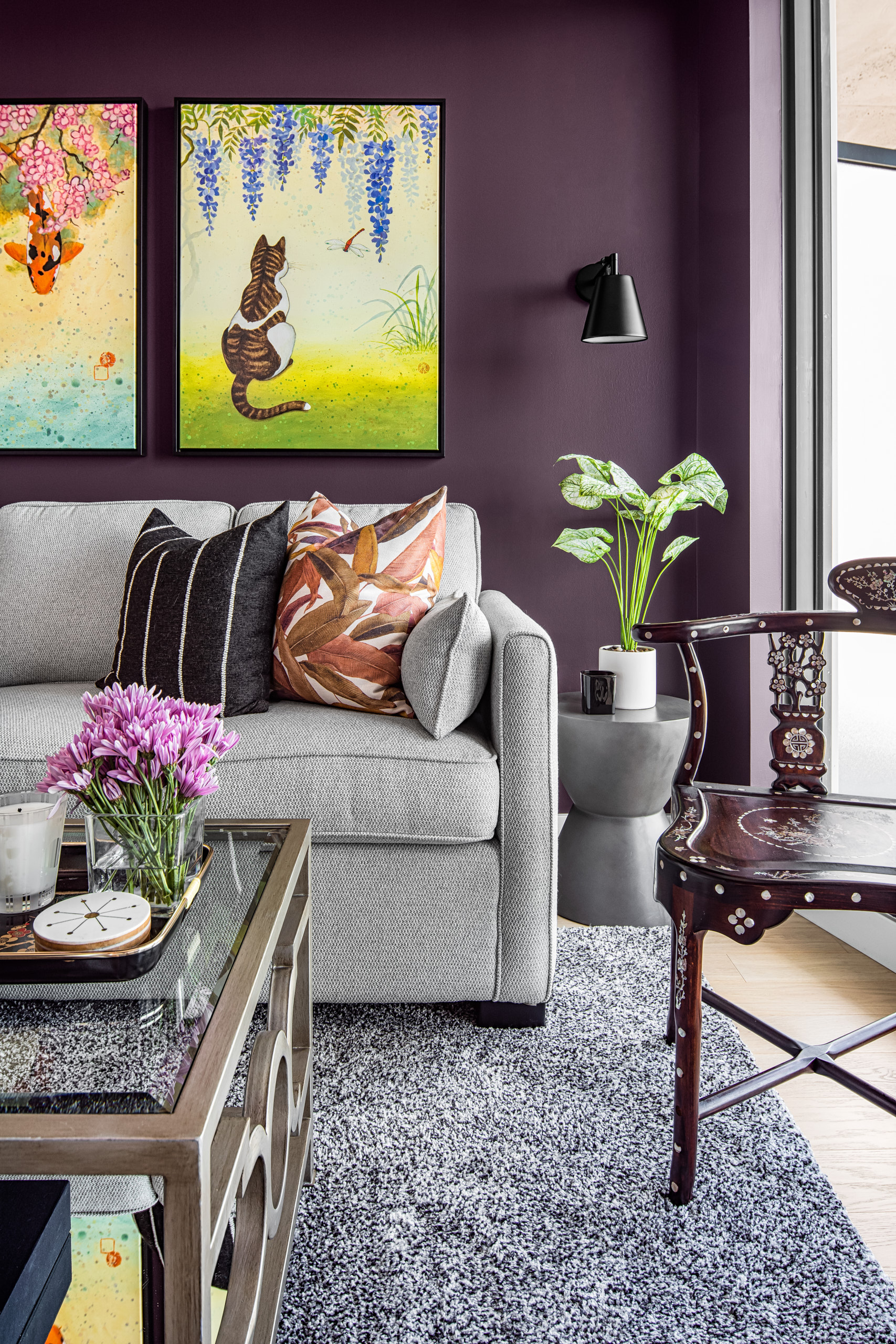 Close up of a grey sofa with patterned pillows against a plum purple wall