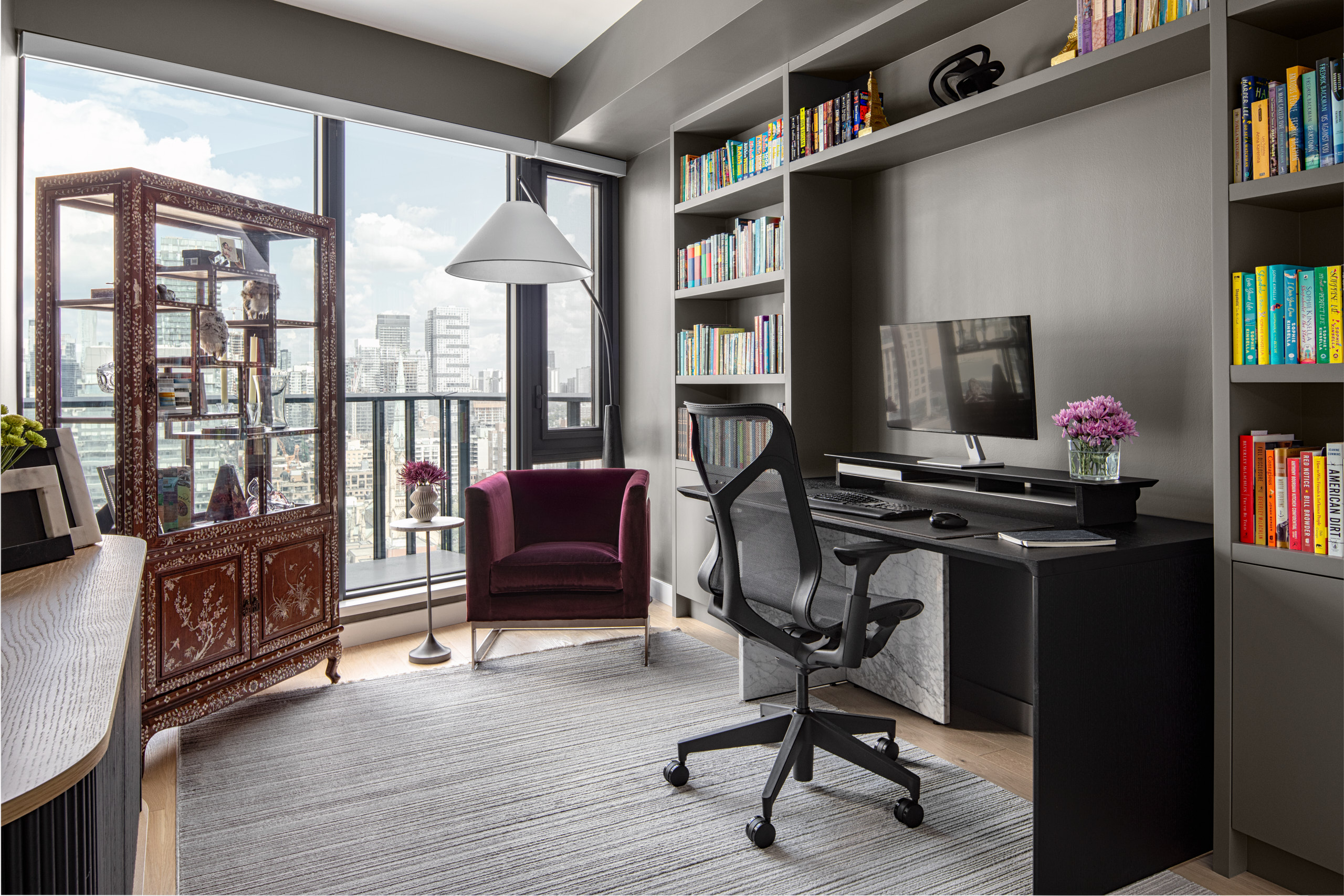 Home office featuring a modern black desk, grey built-ins, and a large antique Chinese curio cabinet open on both sides