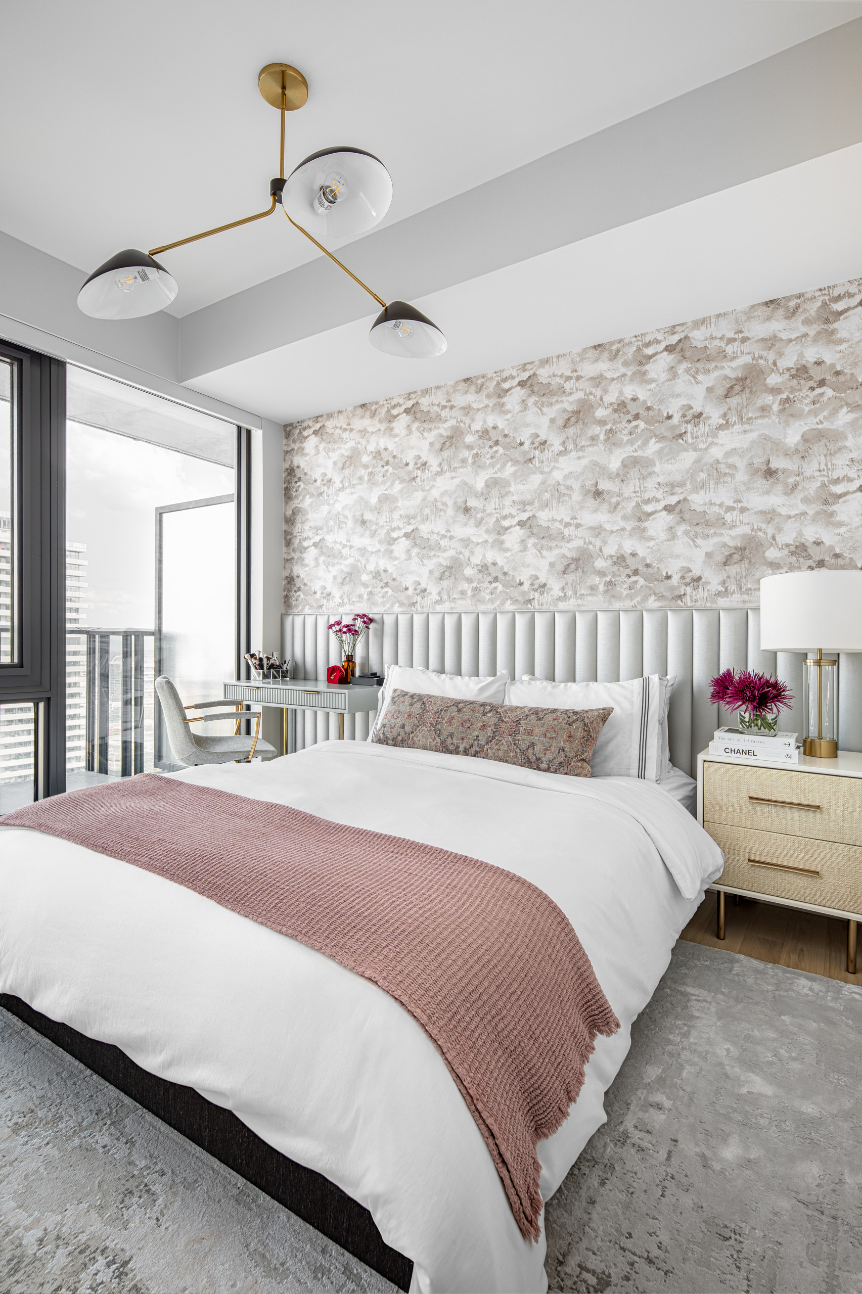 Serene bedroom with landscape wallpaper, a grey fluted headboard, and a modern gold chandelier