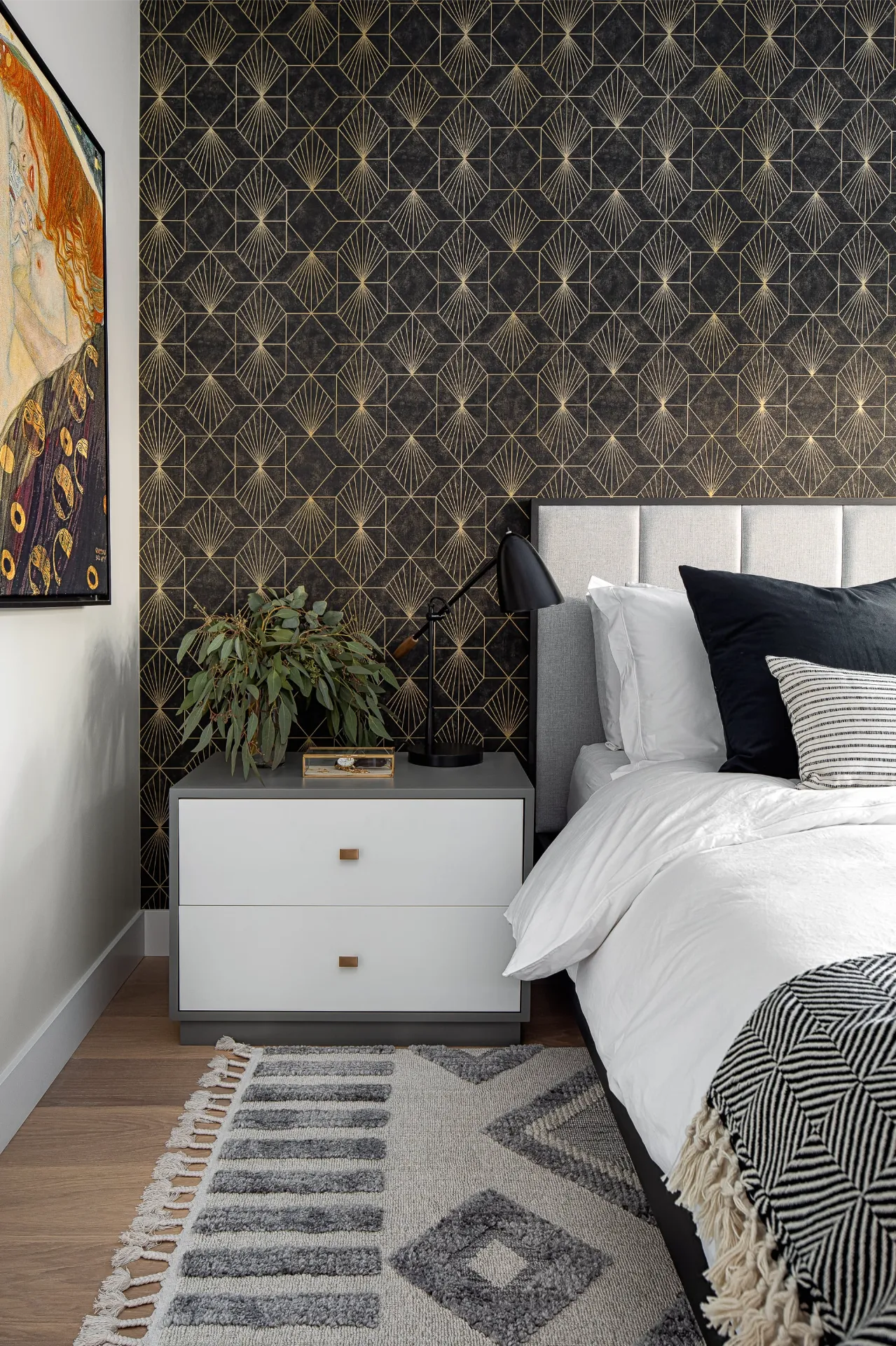 Close up of a grey nightstand against black and gold geometric wallpaper