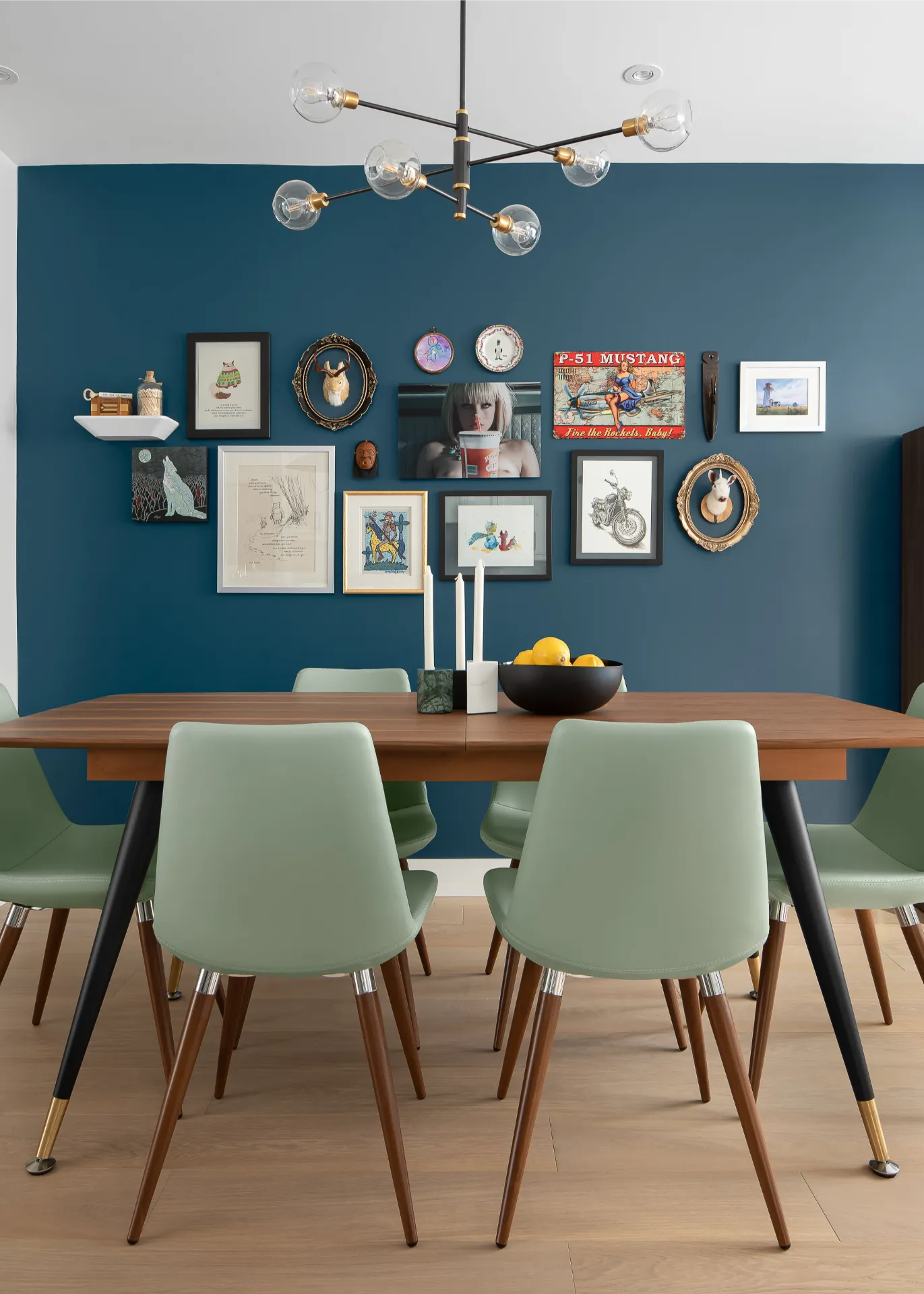 Dining room with a dark blue accent wall, walnut table, and green chairs