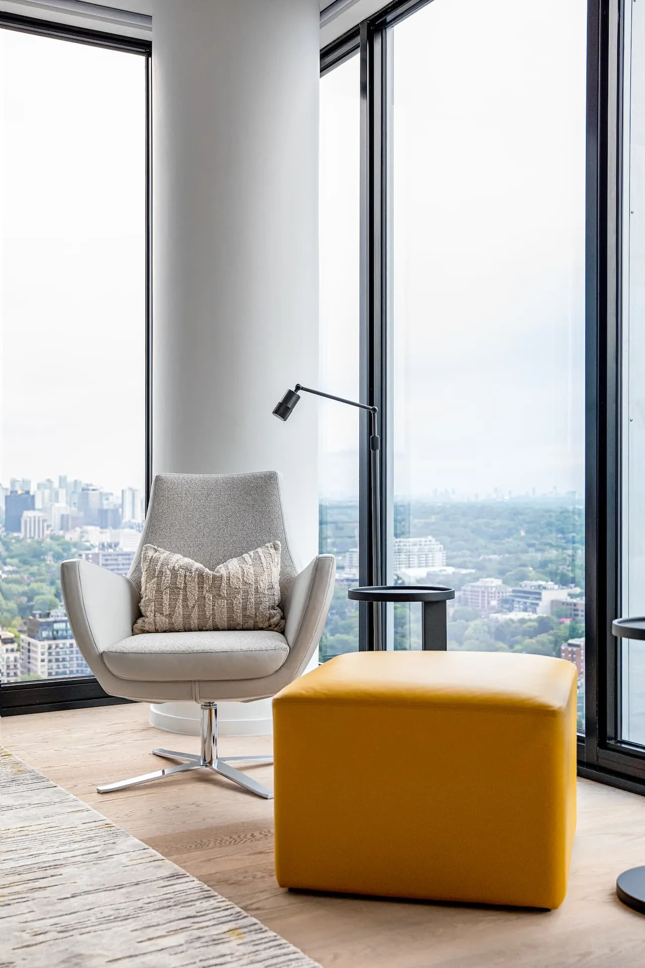 Grey Italian swivel armchair next to a mustard ottoman in a primary bedroom