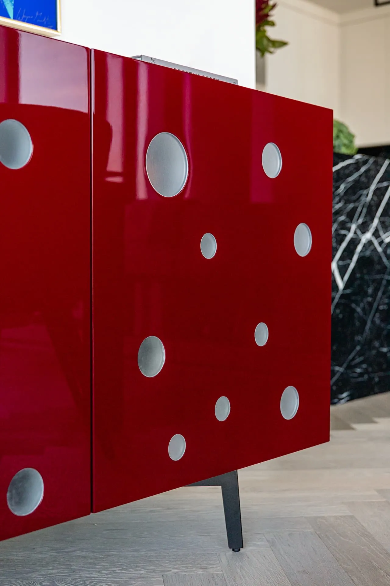 Magnifying glass resting on a book atop a glossy red sideboard with polka dots