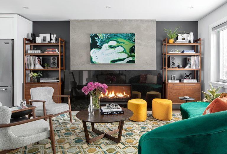 Valleyview Toronto mid-century modern living room with custom emerald green rounded velvet sofa, linear gas fireplace with black granite surround, warm walnut open shelves, and colourful abstract art by Level Studio