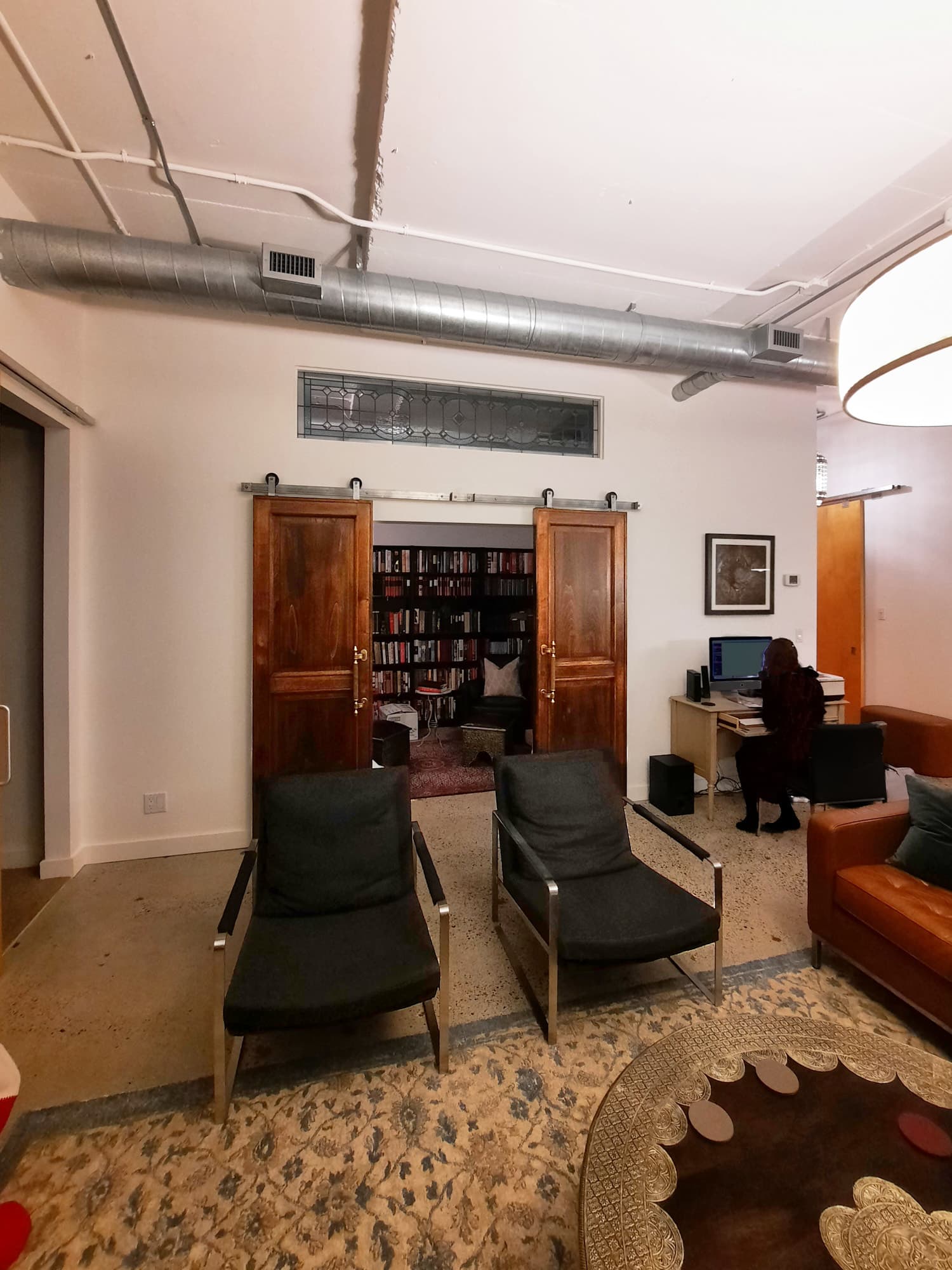 Den before renovation with dark barn doors and stained glass transom