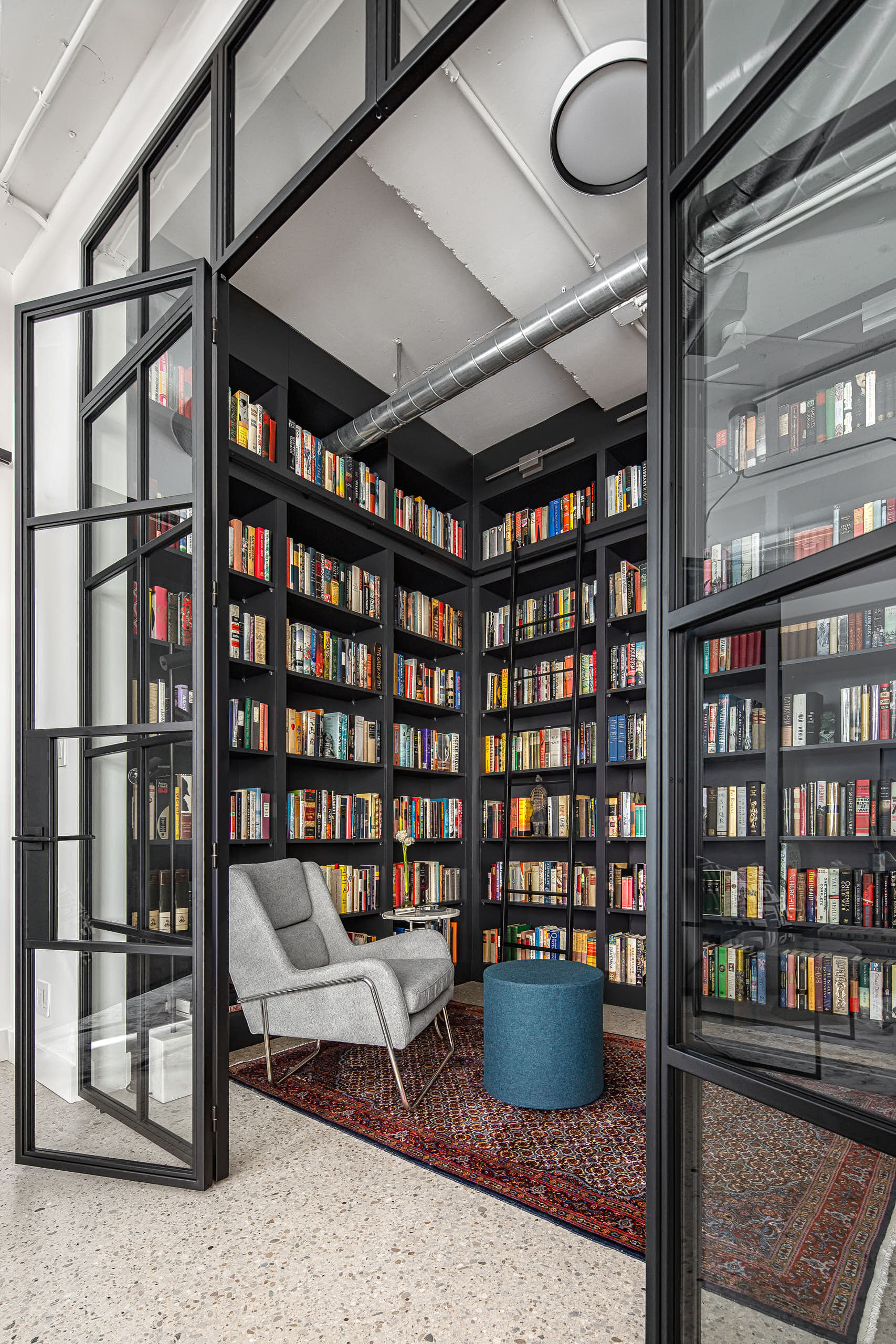 Reading chair inside the custom library with black shelving wrapping two walls