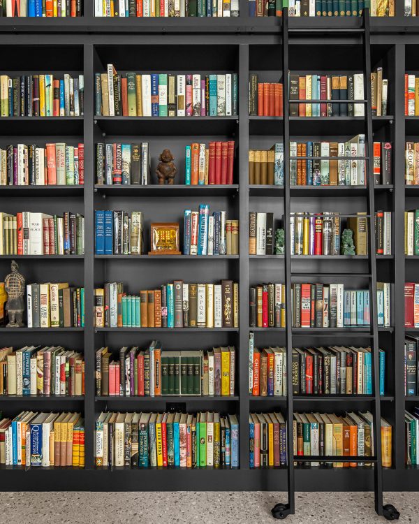 Custom black library shelving with hook-on ladder and books floor to ceiling