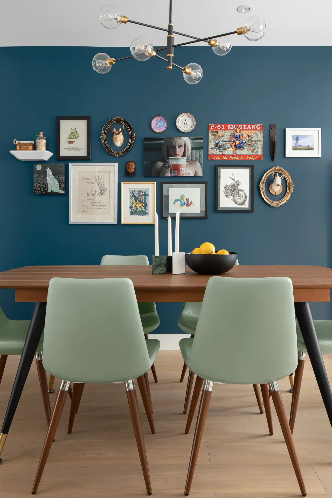 Eclectic gallery wall on a dark blue accent wall behind a modern dining table