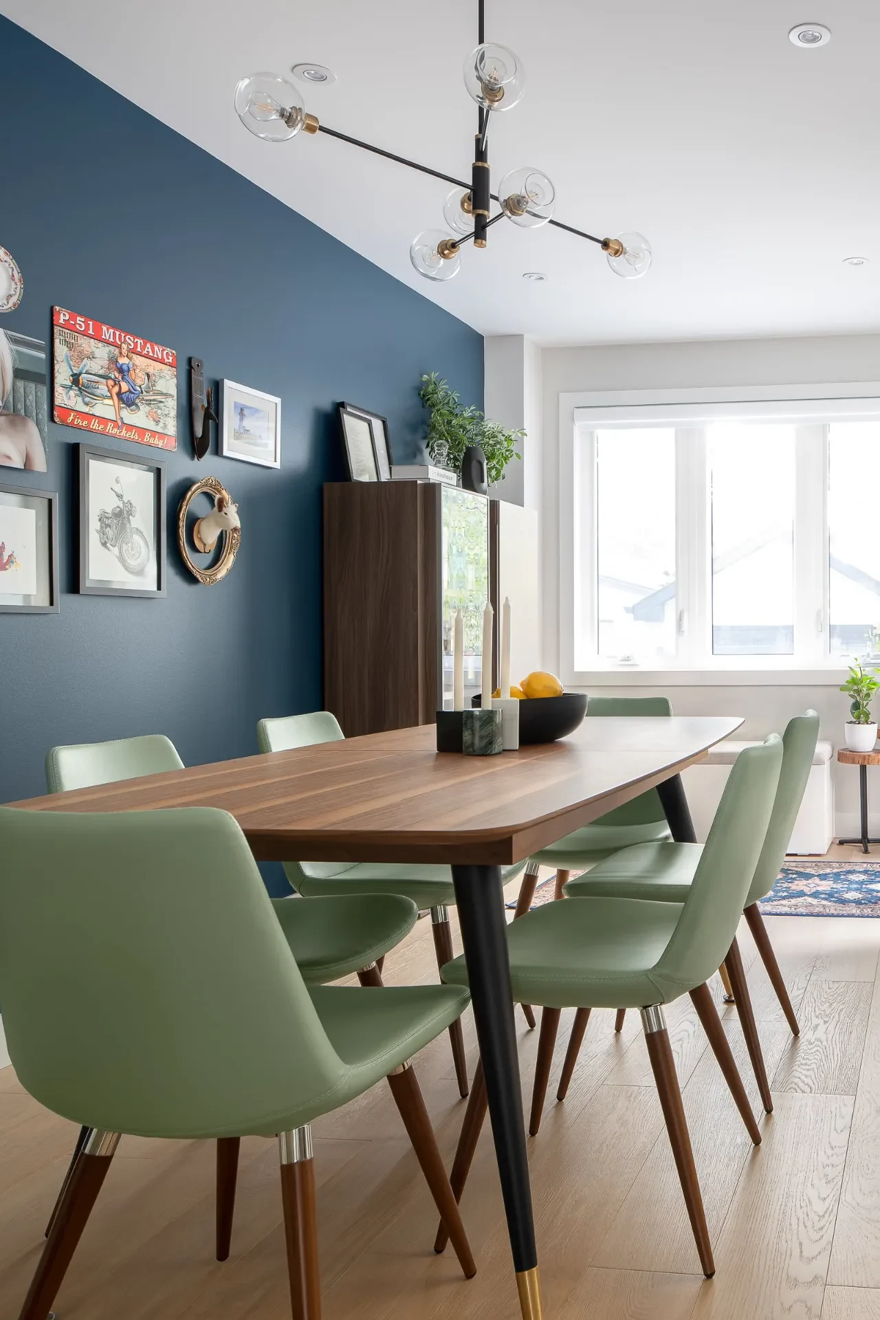 Eclectic gallery wall on a dark teal dining room wall with mint green chairs